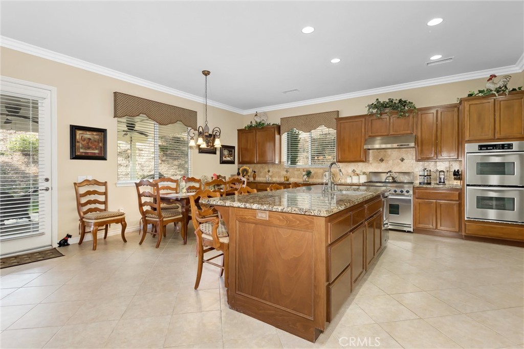 9841 Kehl Canyon Road Beaumont, CA 92223 - Photo 13 of 57 a kitchen with stainless steel appliances granite countertop a stove top oven a sink dishwasher a dining table and chairs with wooden floor