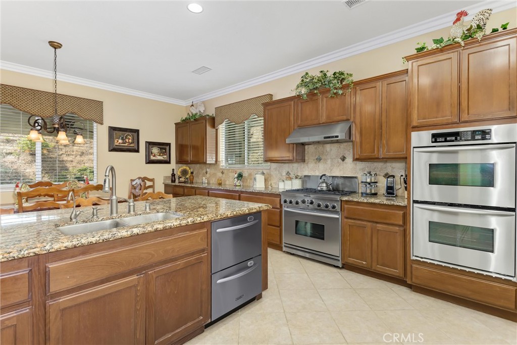 9841 Kehl Canyon Road Beaumont, CA 92223 - Photo 19 of 57 a kitchen with kitchen island granite countertop a sink cabinets and stainless steel appliances