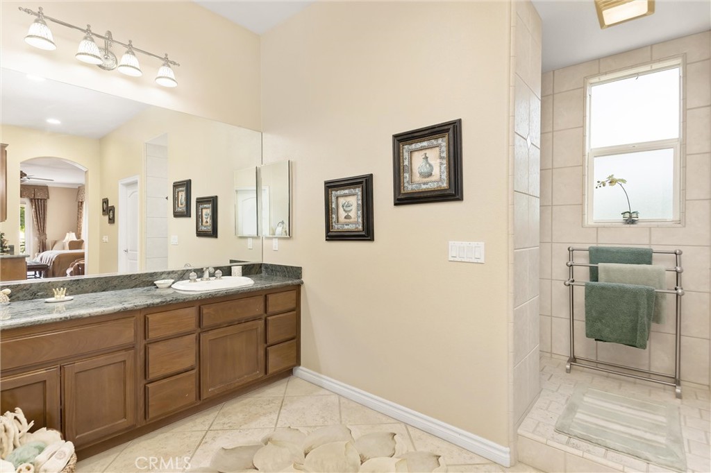 9841 Kehl Canyon Road Beaumont, CA 92223 - Photo 40 of 57 a spacious bathroom with a granite countertop sink a mirror and a shower