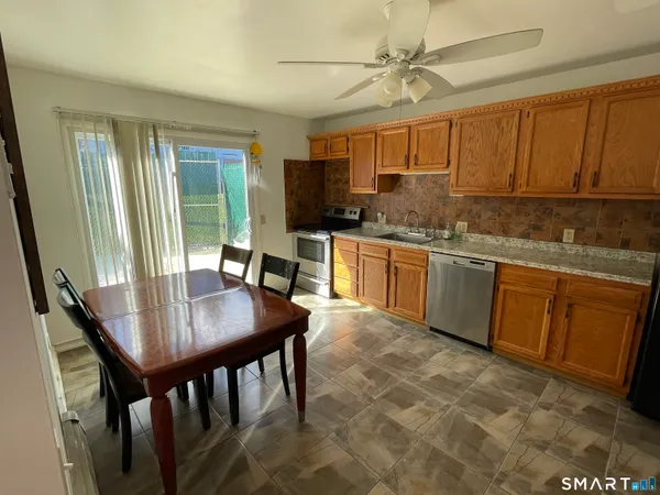 a kitchen with stainless steel appliances granite countertop a stove top oven a sink a dining table and chairs