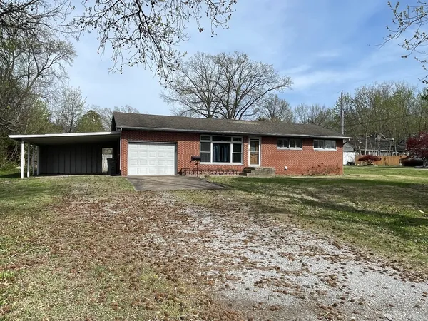 a front view of house with yard and trees in the background
