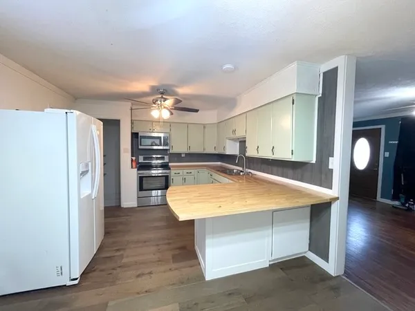a room with kitchen island a sink wooden floor and stainless steel appliances