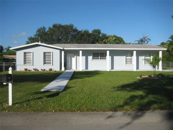 a front view of a house with a garden and trees