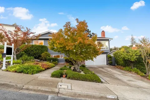 a front view of a house with a yard and potted plants