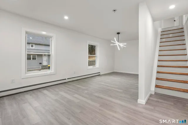 a view of an empty room with a window and wooden floor