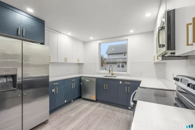 a kitchen with stainless steel appliances granite countertop a sink a stove and a refrigerator