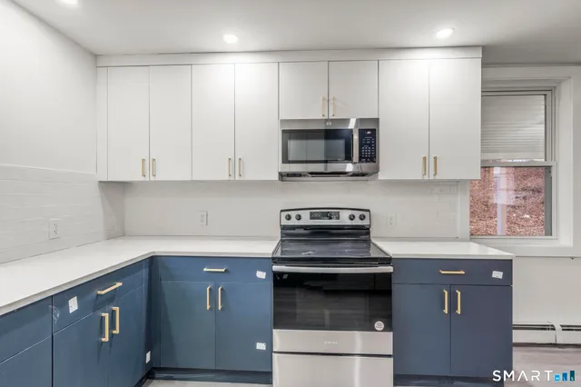 a kitchen with cabinets stainless steel appliances and wooden floor
