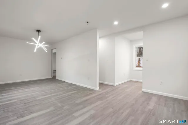 an empty room with wooden floor ceiling fan and windows