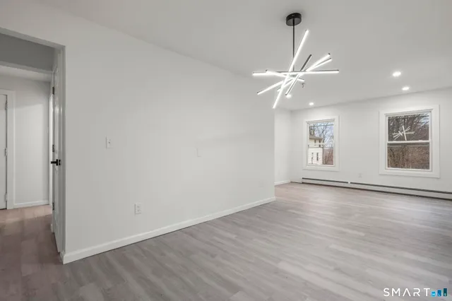 an empty room with wooden floor fan and windows