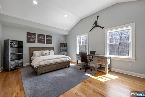 a bedroom with a bed wooden floor and windows