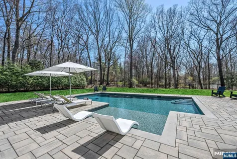 a view of pool with table and chairs under an umbrella