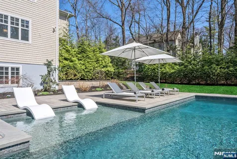 a view of pool with lawn chairs under an umbrella