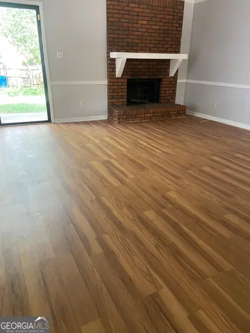 a view of empty room with wooden floor and fireplace