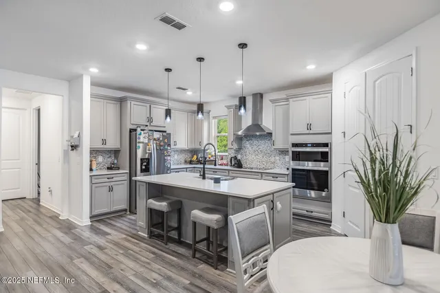 a kitchen with stainless steel appliances a sink a stove a refrigerator cabinets and wooden floor