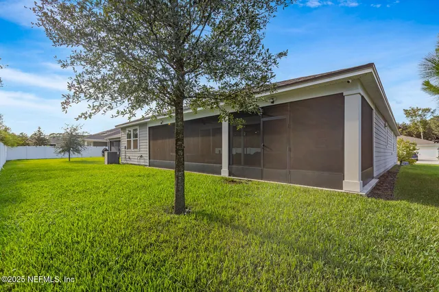 a backyard of a house with plants and large tree
