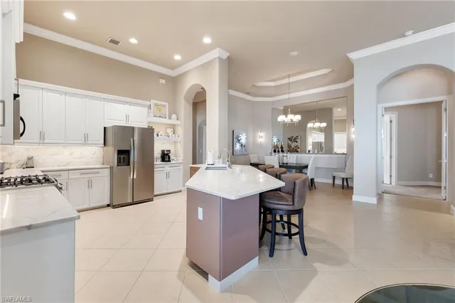 a kitchen with stainless steel appliances kitchen island granite countertop a table chairs sink and cabinets
