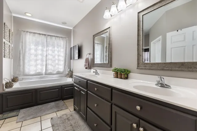 a bathroom with a double vanity sink bathtub and next to a window
