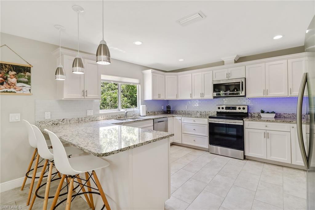 a kitchen with granite countertop a stove top oven a sink a dining table and chairs