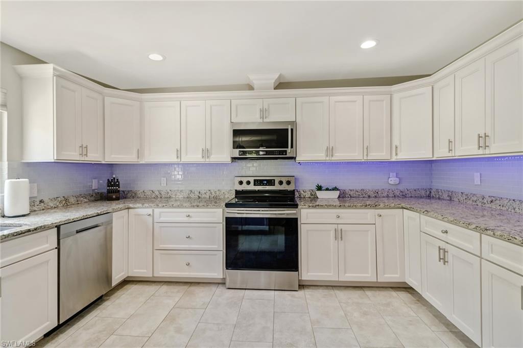 4355 Pine Ridge Road Naples, FL 34119 - Photo 18 of 23 a kitchen with granite countertop white cabinets and stainless steel appliances