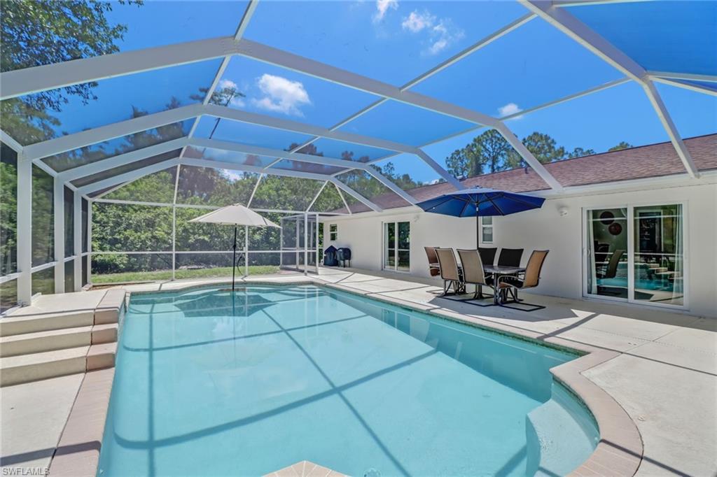 4355 Pine Ridge Road Naples, FL 34119 - Photo 19 of 23 a view of a backyard with table and chairs under an umbrella