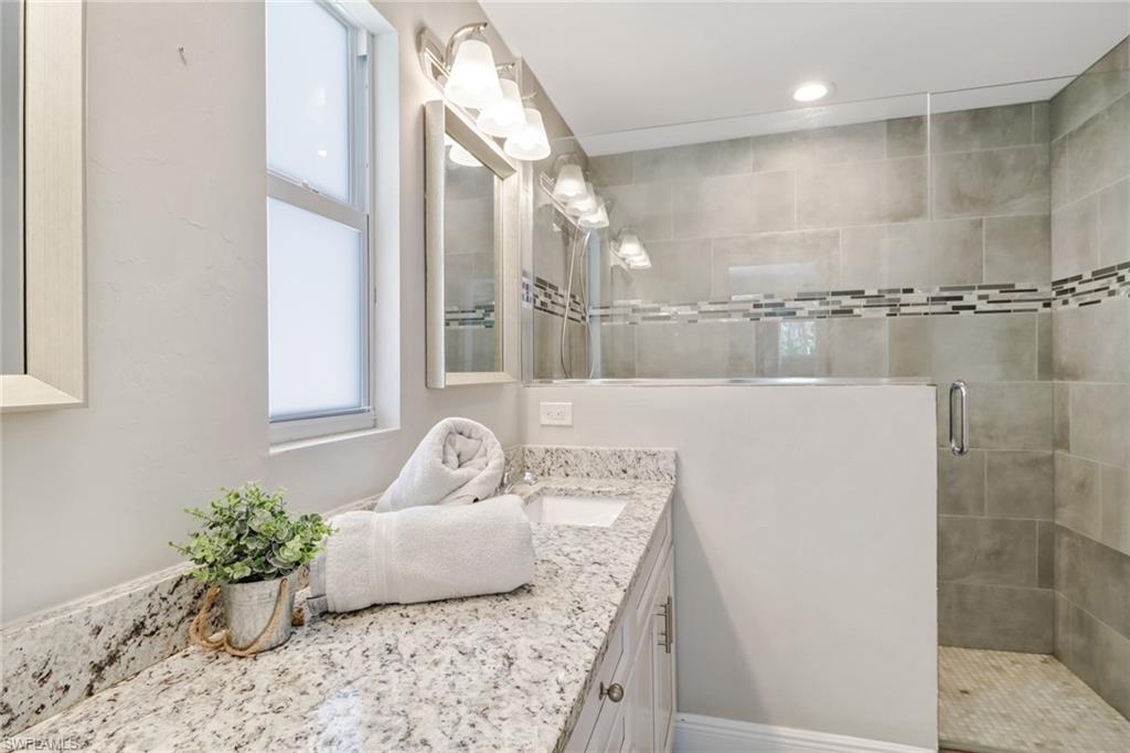 4355 Pine Ridge Road Naples, FL 34119 - Photo 3 of 23 a bathroom with a granite countertop sink a mirror and shower