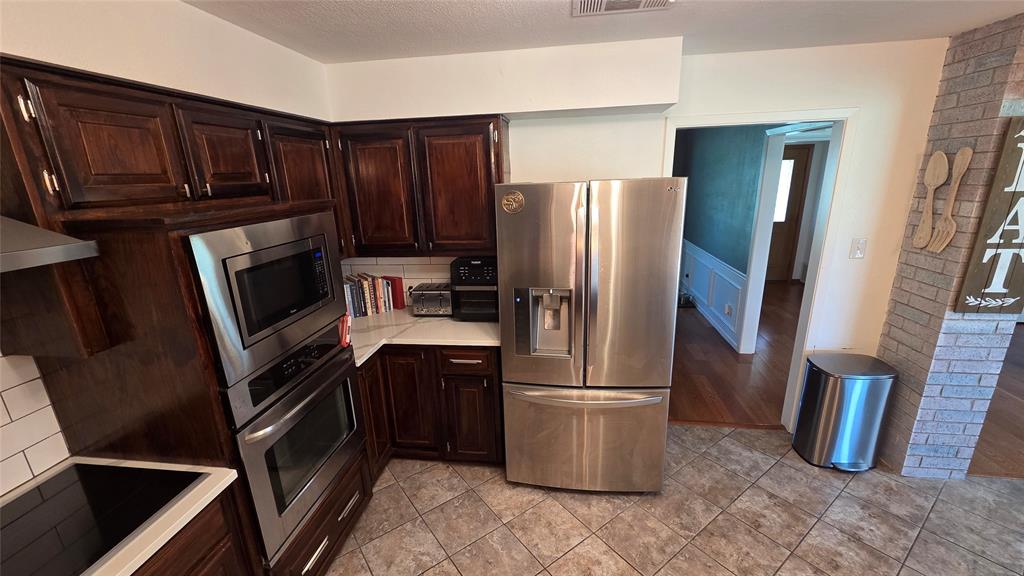 338 Travis Road Decatur, TX 76234 - Photo 12 of 40 a kitchen with stainless steel appliances granite countertop a refrigerator microwave and wooden cabinets
