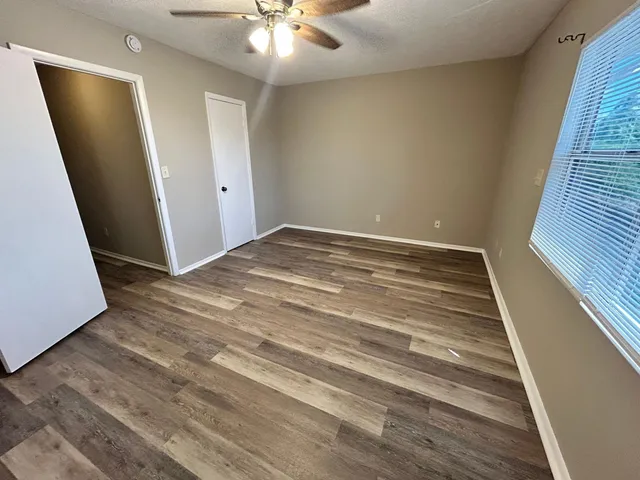 a view of empty room with wooden floor and fan