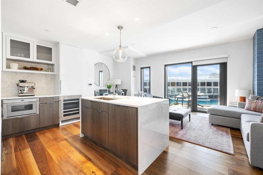 300 Pier 4 Blvd., Unit 3K Boston, MA 02210 - Photo 3 of 24 a large kitchen with kitchen island a large counter top space a sink a stove and wooden floor