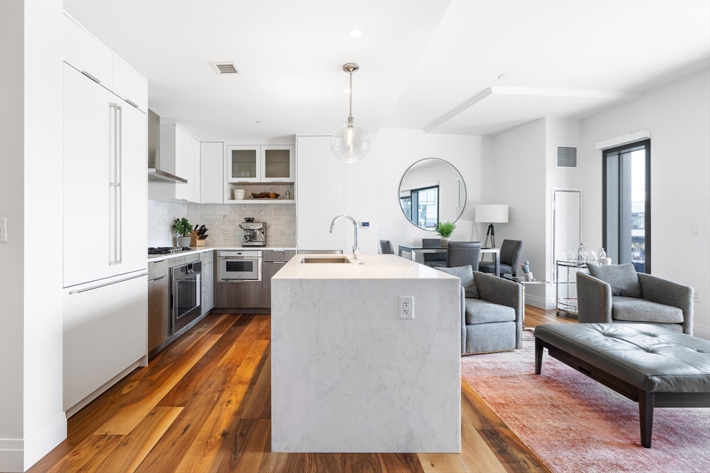 300 Pier 4 Blvd., Unit 3K Boston, MA 02210 - Photo 6 of 24 a living room with stainless steel appliances furniture a rug and a kitchen view