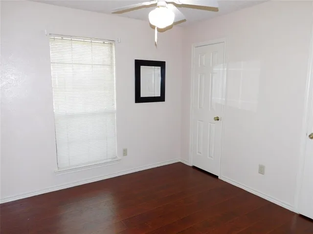 an empty room with wooden floor cabinet and windows