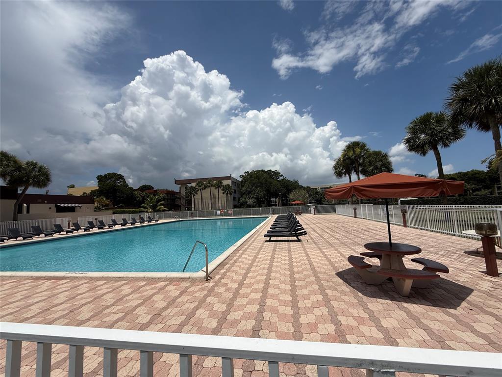 a view of swimming pool with seating space and trees in the background