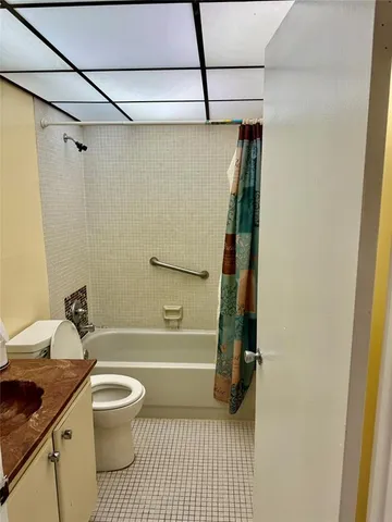 a bathroom with a granite countertop bathtub shower sink vanity and toilet
