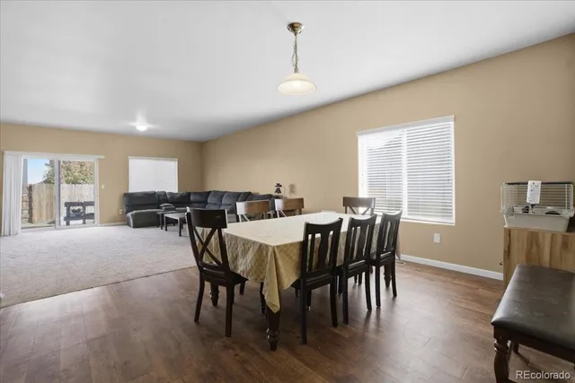 a kitchen with stainless steel appliances granite countertop a refrigerator a stove a sink a dining table and chairs with wooden floor