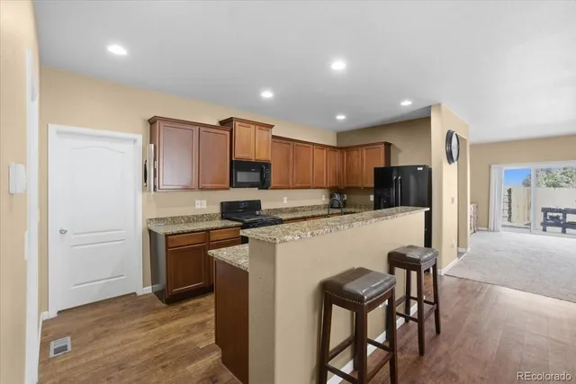 a kitchen with stainless steel appliances granite countertop a stove top oven a sink dishwasher and a refrigerator with wooden floor