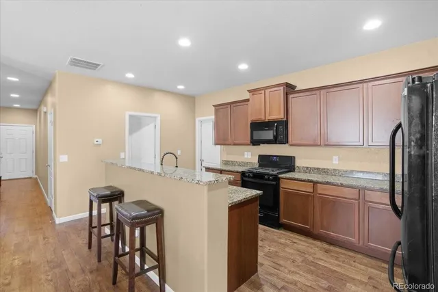 a kitchen with stainless steel appliances granite countertop a kitchen island a stove a sink and a refrigerator