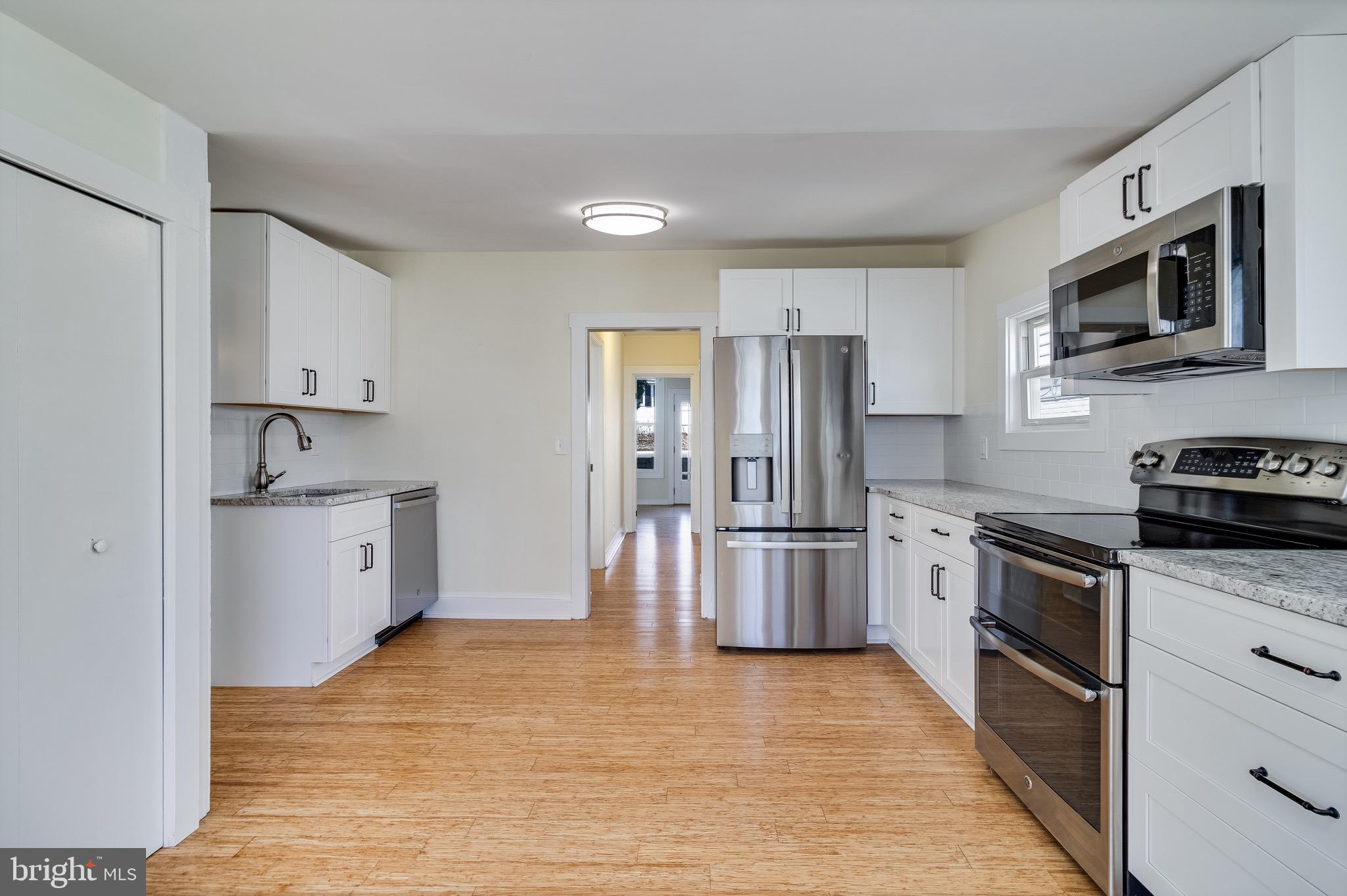 8227 Bayside Road Chesapeake Beach, MD 20732 - Photo 5 of 27 a kitchen with stainless steel appliances granite countertop a stove top oven a refrigerator a sink and dishwasher with wooden floor
