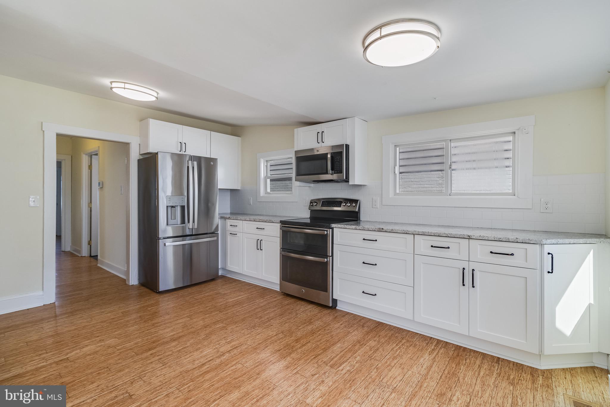 8227 Bayside Road Chesapeake Beach, MD 20732 - Photo 10 of 27 a kitchen with stainless steel appliances white cabinets and wooden floors