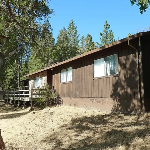 a backyard of a house with large tree and wooden fence