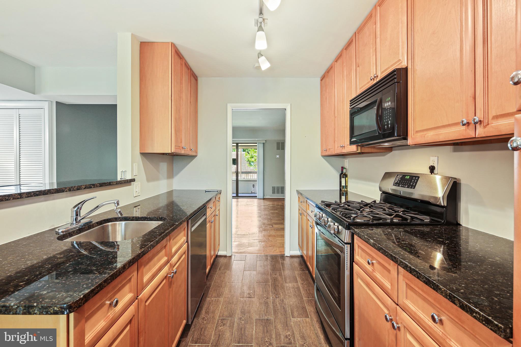 5239 West Running Brook Road, Unit 301 Columbia, MD 21044 - Photo 10 of 33 a kitchen with granite countertop stainless steel appliances a sink stove top oven and cabinets