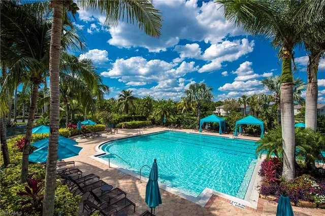 a view of a swimming pool with lawn chairs under an umbrella