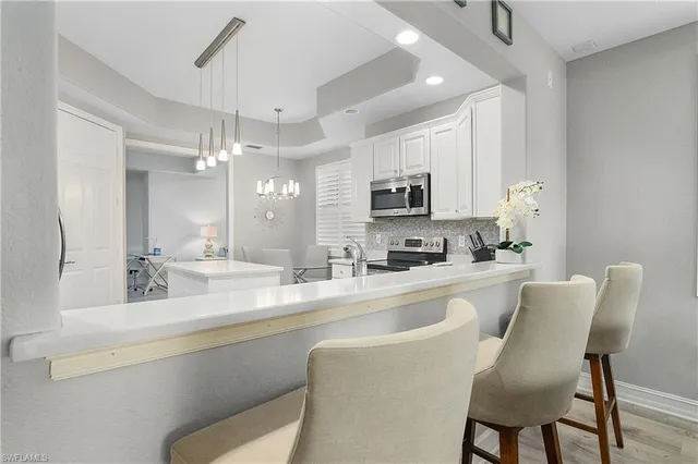 a kitchen with kitchen island granite countertop a dining table chairs cabinets and stainless steel appliances