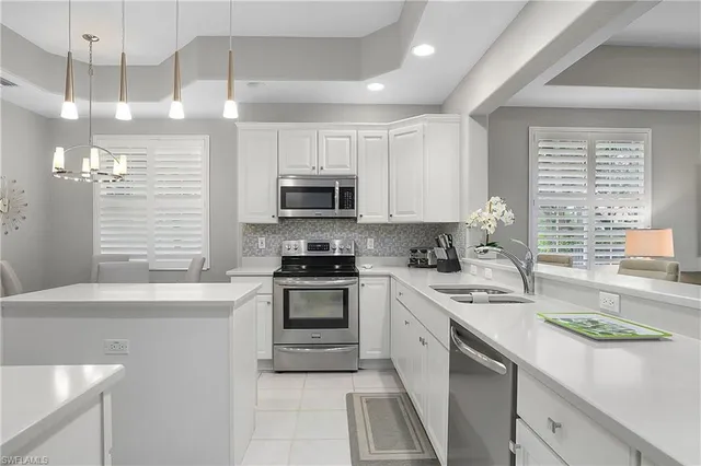 a kitchen with stainless steel appliances granite countertop a sink a stove a refrigerator cabinets and a window