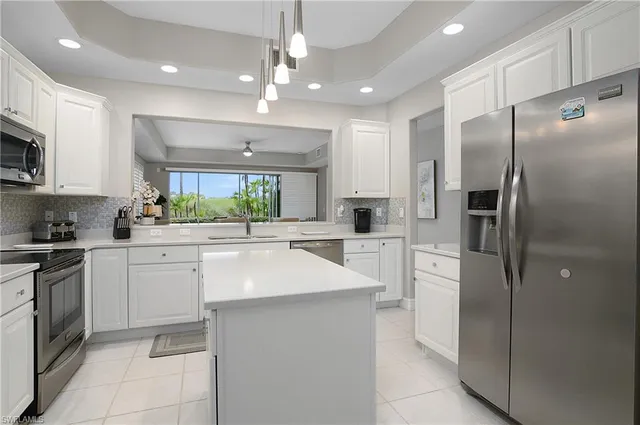 a kitchen with stainless steel appliances kitchen island granite countertop a refrigerator and a sink