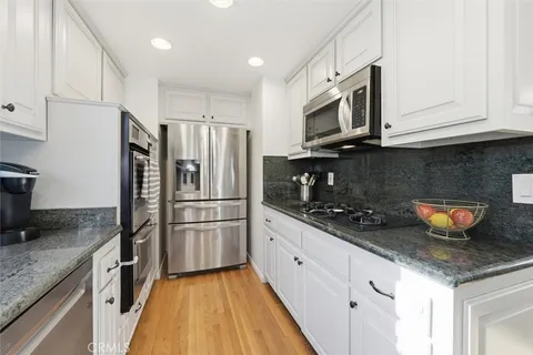 a kitchen with granite countertop a sink stainless steel appliances and cabinets