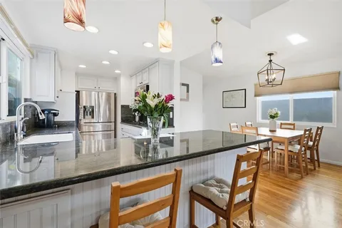 a kitchen with granite countertop a table chairs and wooden floor
