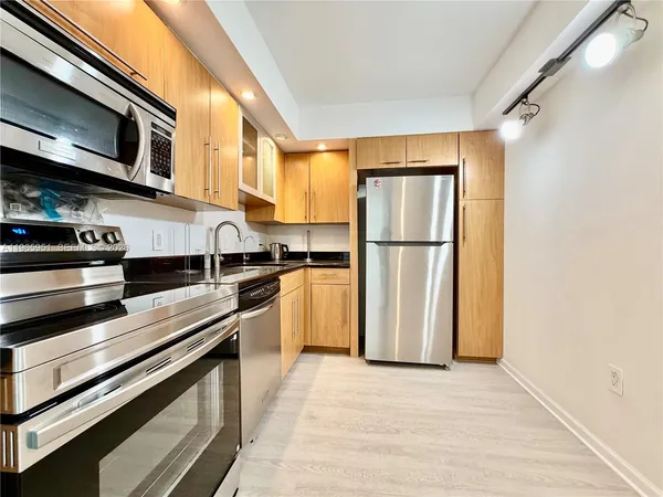 a kitchen with stainless steel appliances a refrigerator a stove top oven a sink and cabinets