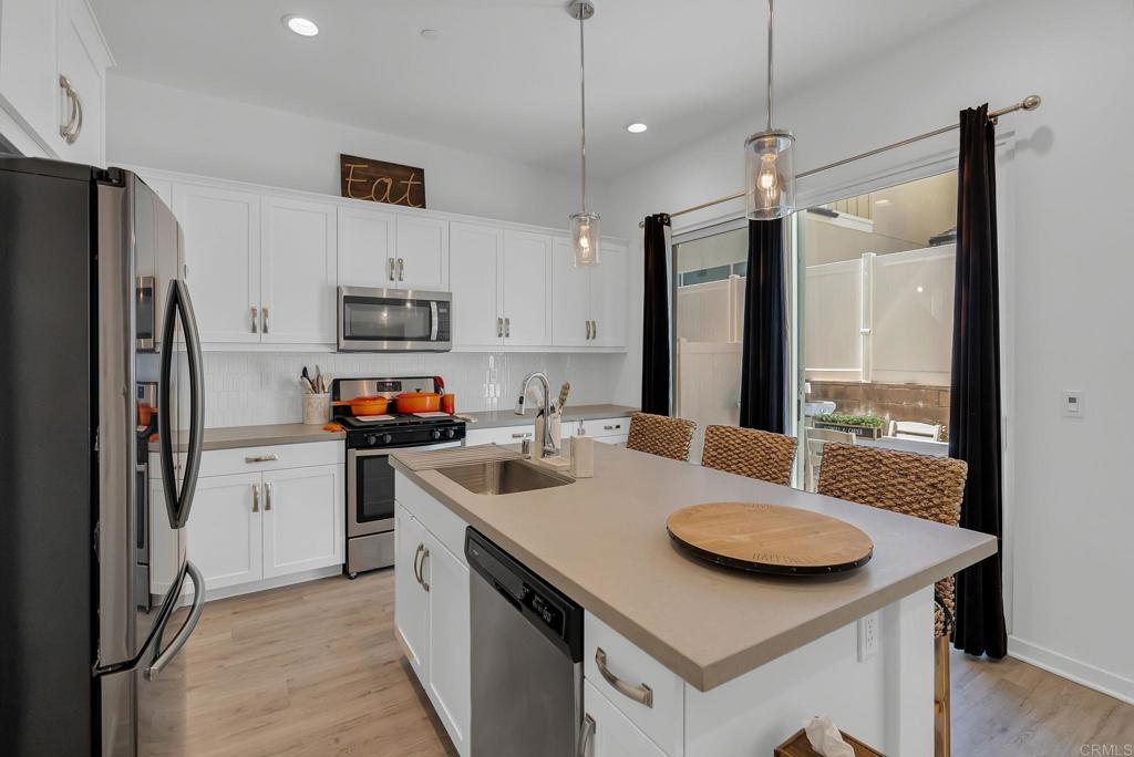 a kitchen that has a sink a center island stainless steel appliances and a chandelier