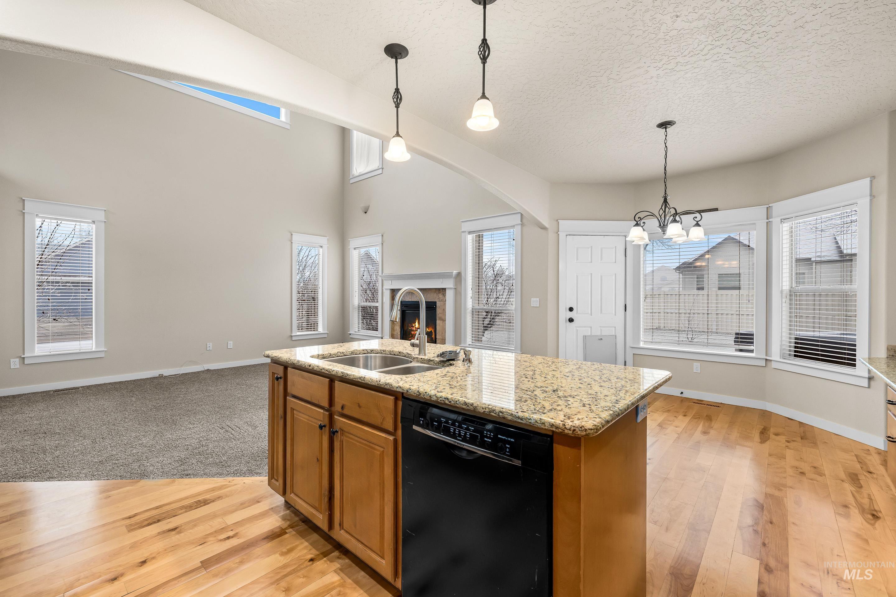 2578 South Groom Way Meridian, ID 83642 - Photo 39 of 39 Kitchen with brown cabinetry, black dishwasher, hanging light fixtures, a lit fireplace, and open floor plan