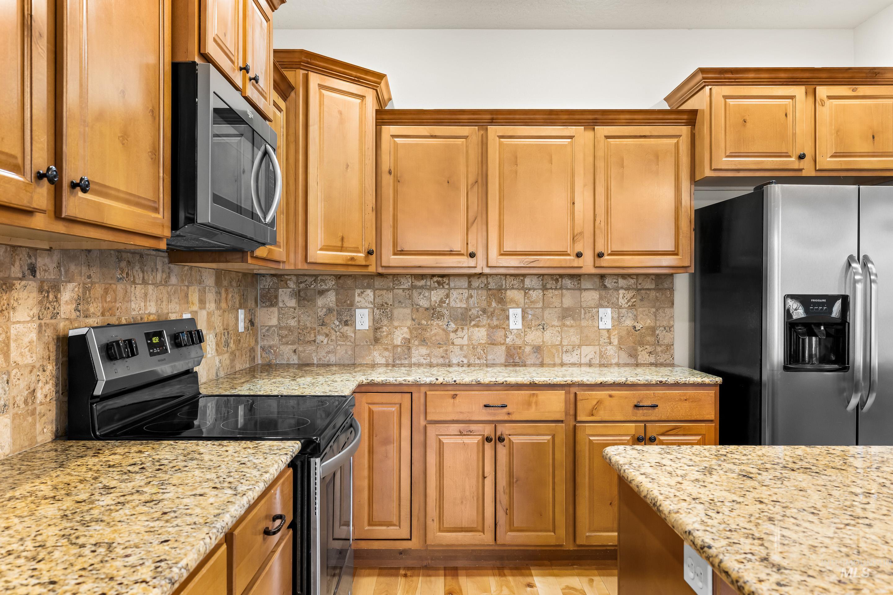 2578 South Groom Way Meridian, ID 83642 - Photo 13 of 39 Kitchen featuring stainless steel appliances, brown cabinets, light stone counters, and tasteful backsplash