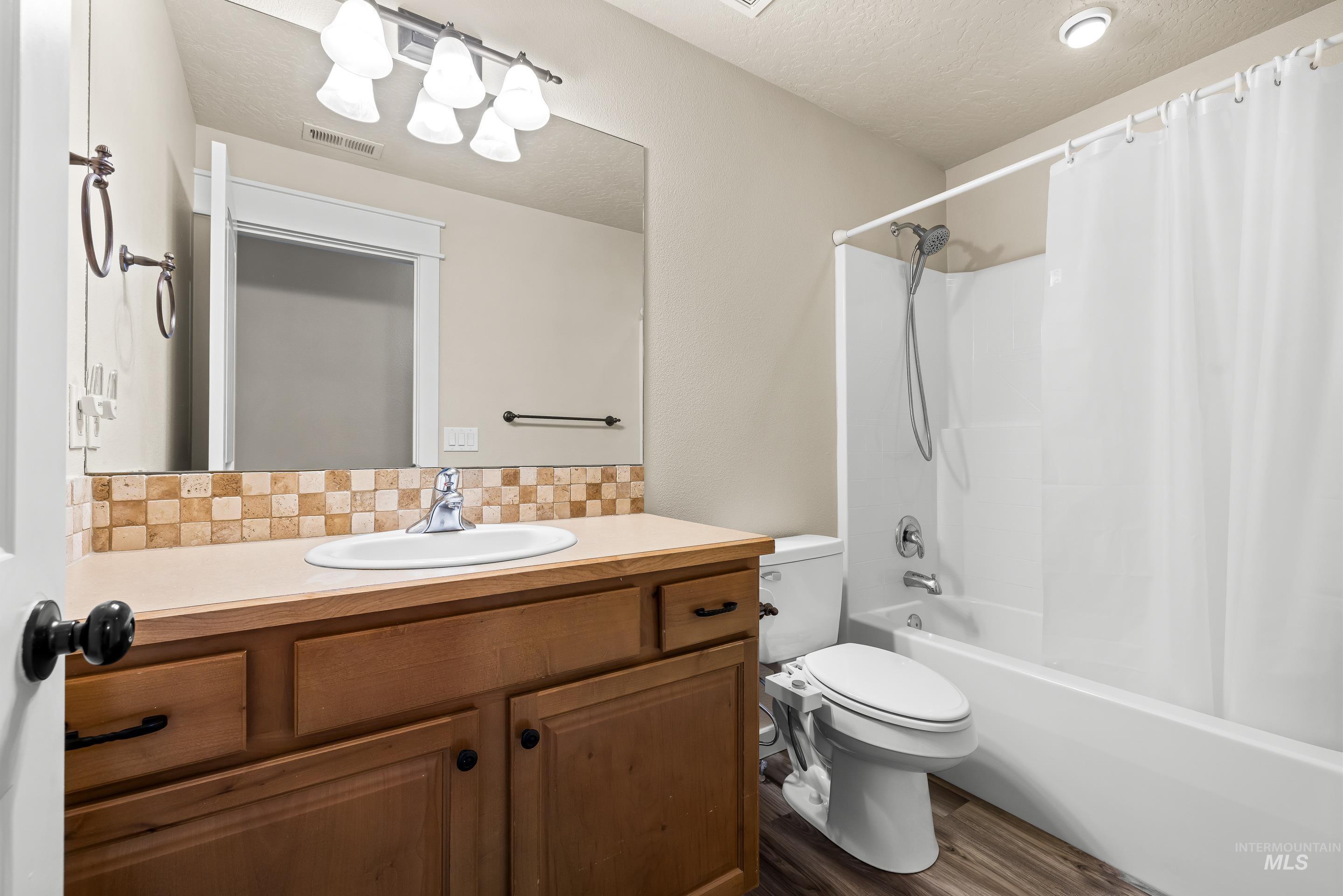 2578 South Groom Way Meridian, ID 83642 - Photo 29 of 39 Bathroom featuring shower / bath combo with shower curtain, vanity, decorative backsplash, a textured ceiling, and dark wood-type flooring
